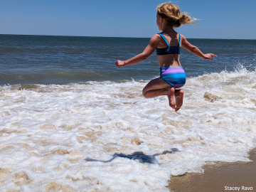 Girl jumping in surf. Photo is a Rehoboth Reflections competition winner.